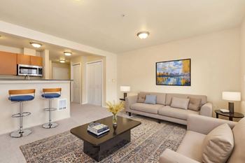 A living room with a sofa, two chairs, a coffee table, and a painting on the wall.
